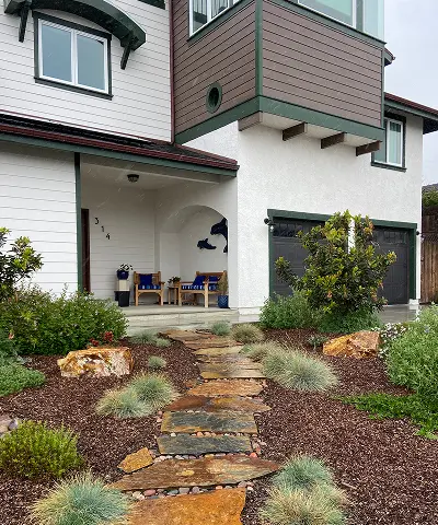 An eco-friendly yard with a stone pathway leading to a front porch