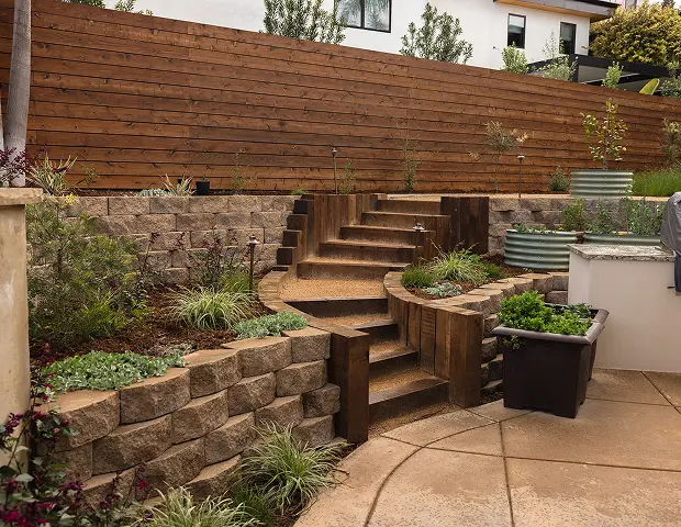 Wooden steps leading up to a path by a wooden wall