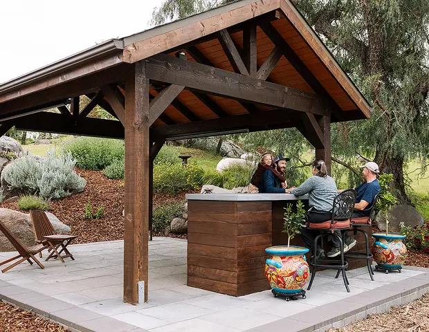 People sitting at a counter under a pergola