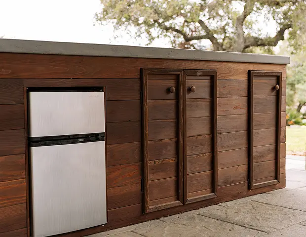 An outdoor counter with a built in fridge and cabinets