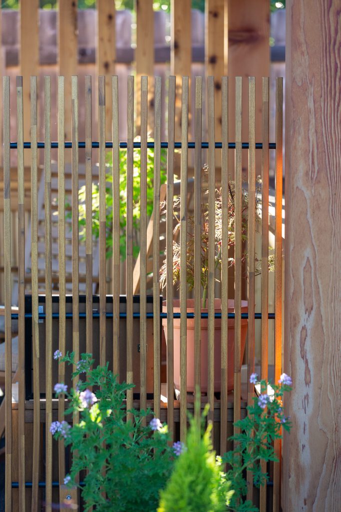 vertical wood-slat privacy screen with layered plantings