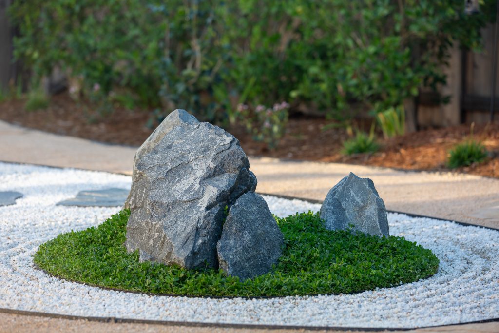Boulder grouping in raked aggregate with moss-green groundcover mounds