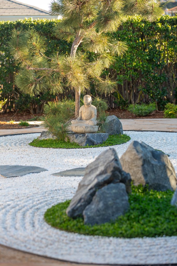 Stone statue framed by black pine and a bamboo privacy screen