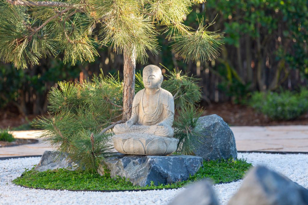 Seated stone statue among boulders and mounded groundcover